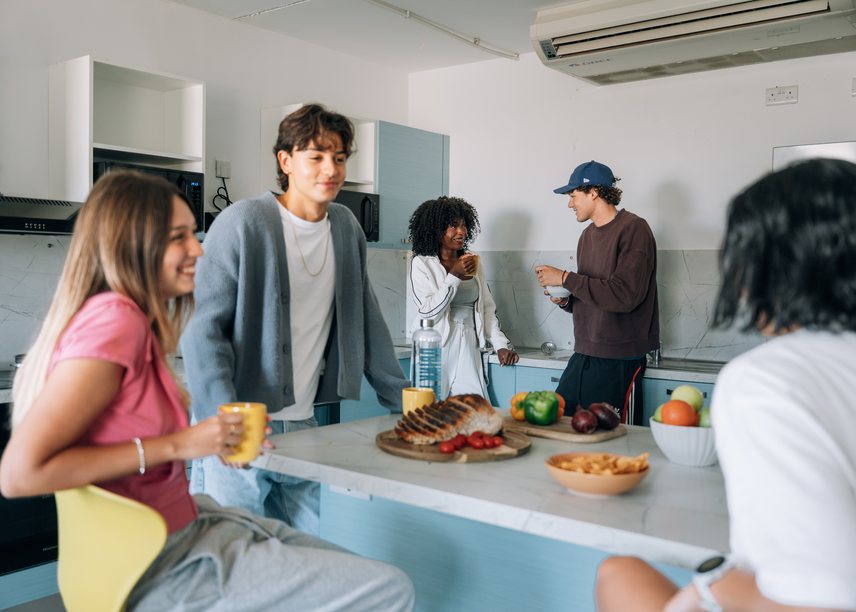 Students talking together over food around a shared kitchen island