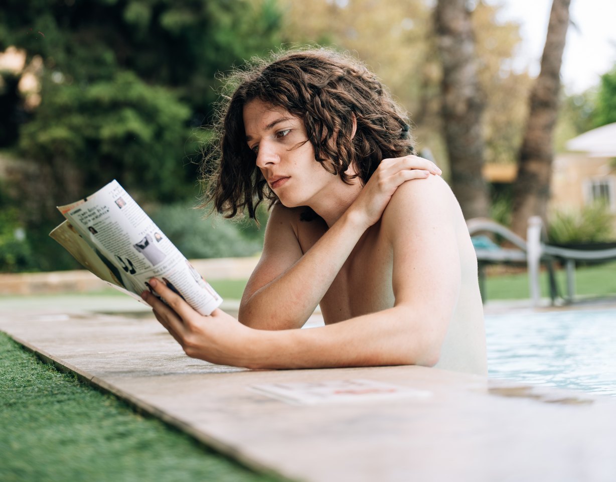 A student reading a magazine beside the pool