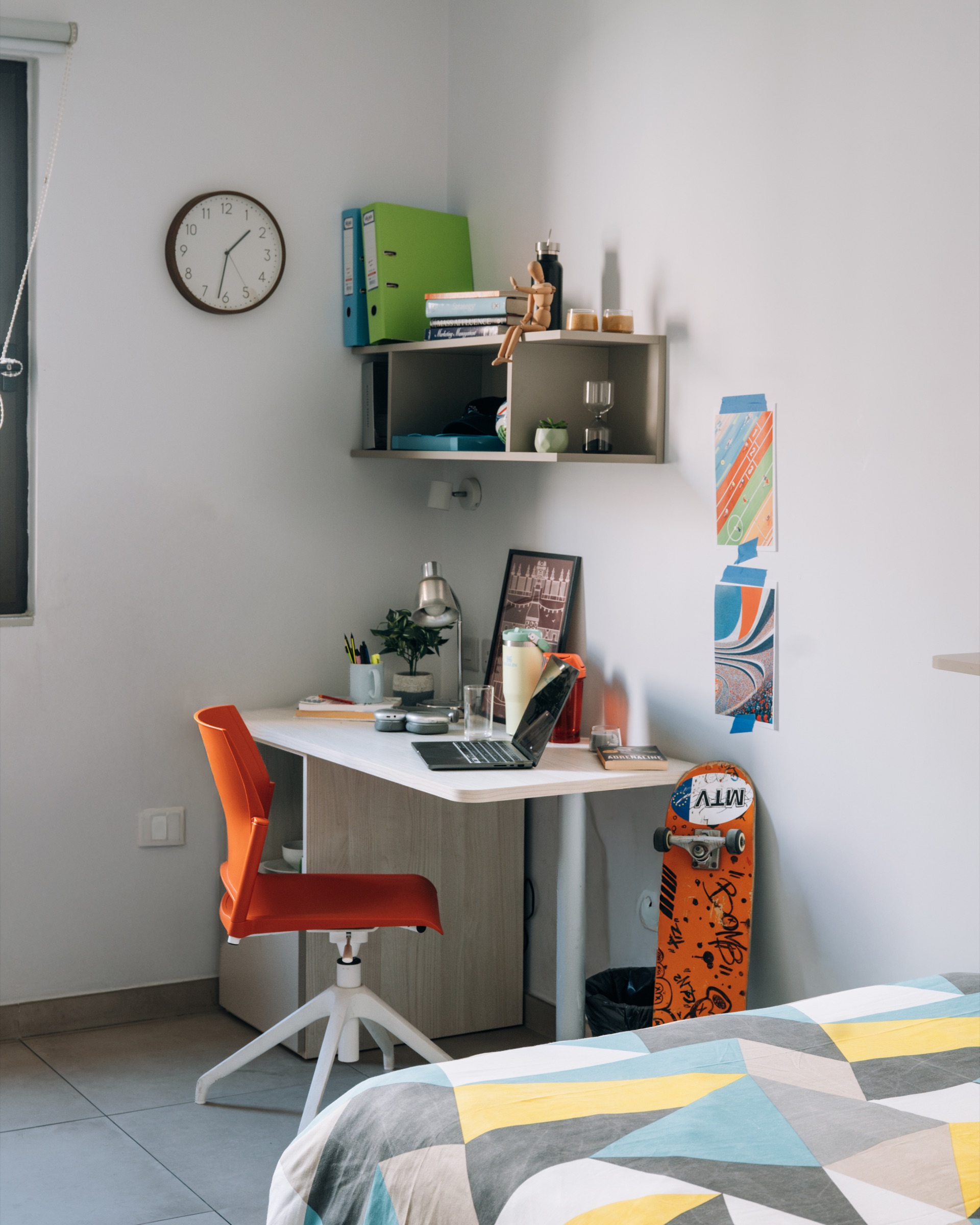 Study corner of a Cosy room, with an orange chair at the desk and a skateboard beside it