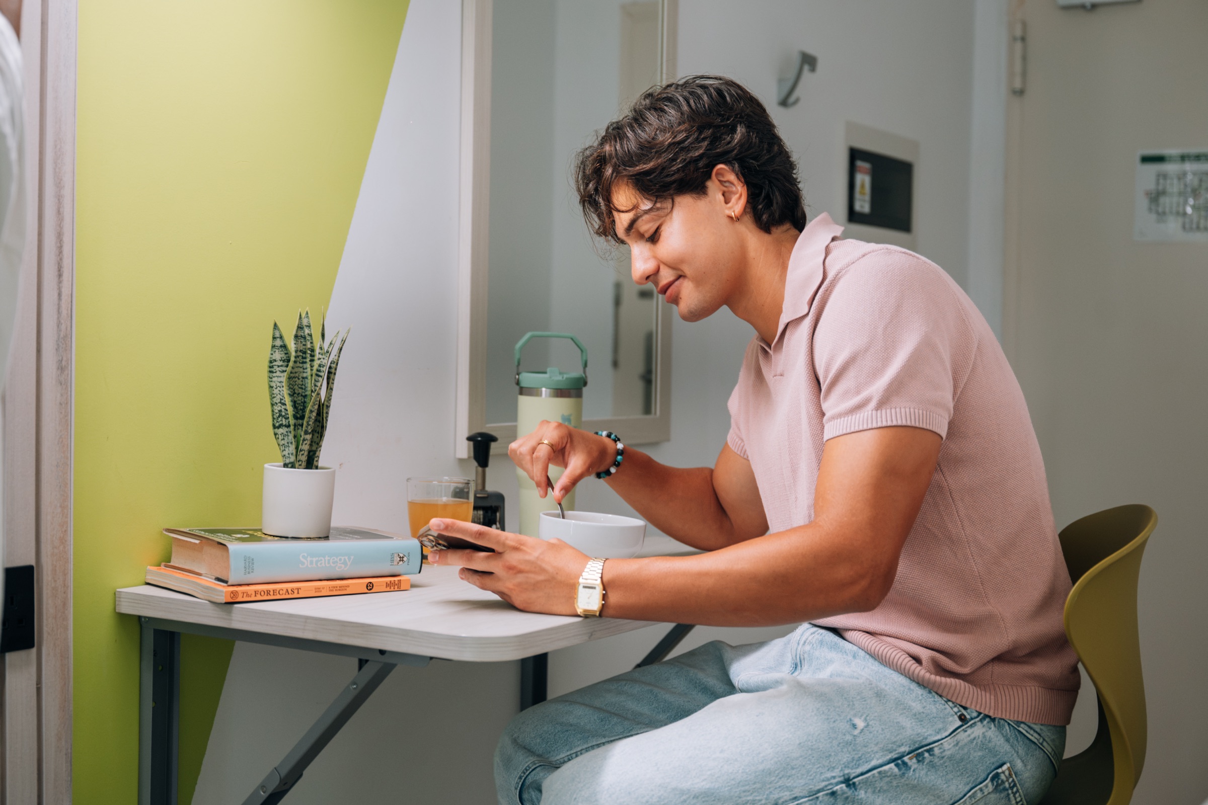 Student eating breakfast at the fold-down table of a Solo room