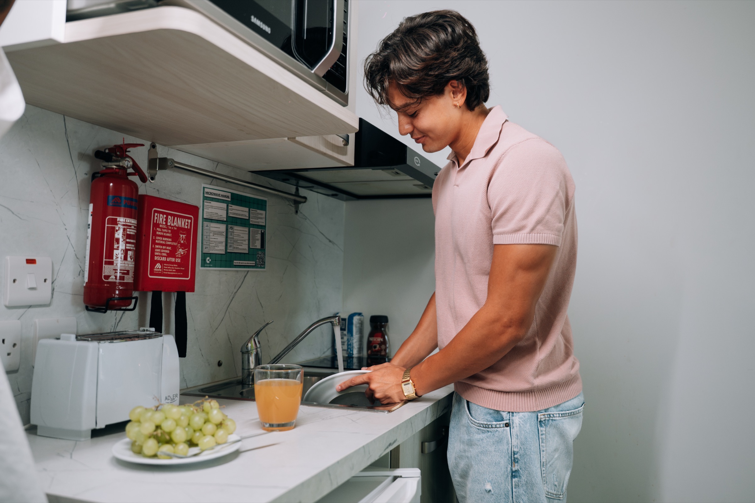 Student at the in-room kitchen sink of a Solo room, with a microwave and toaster on the counter