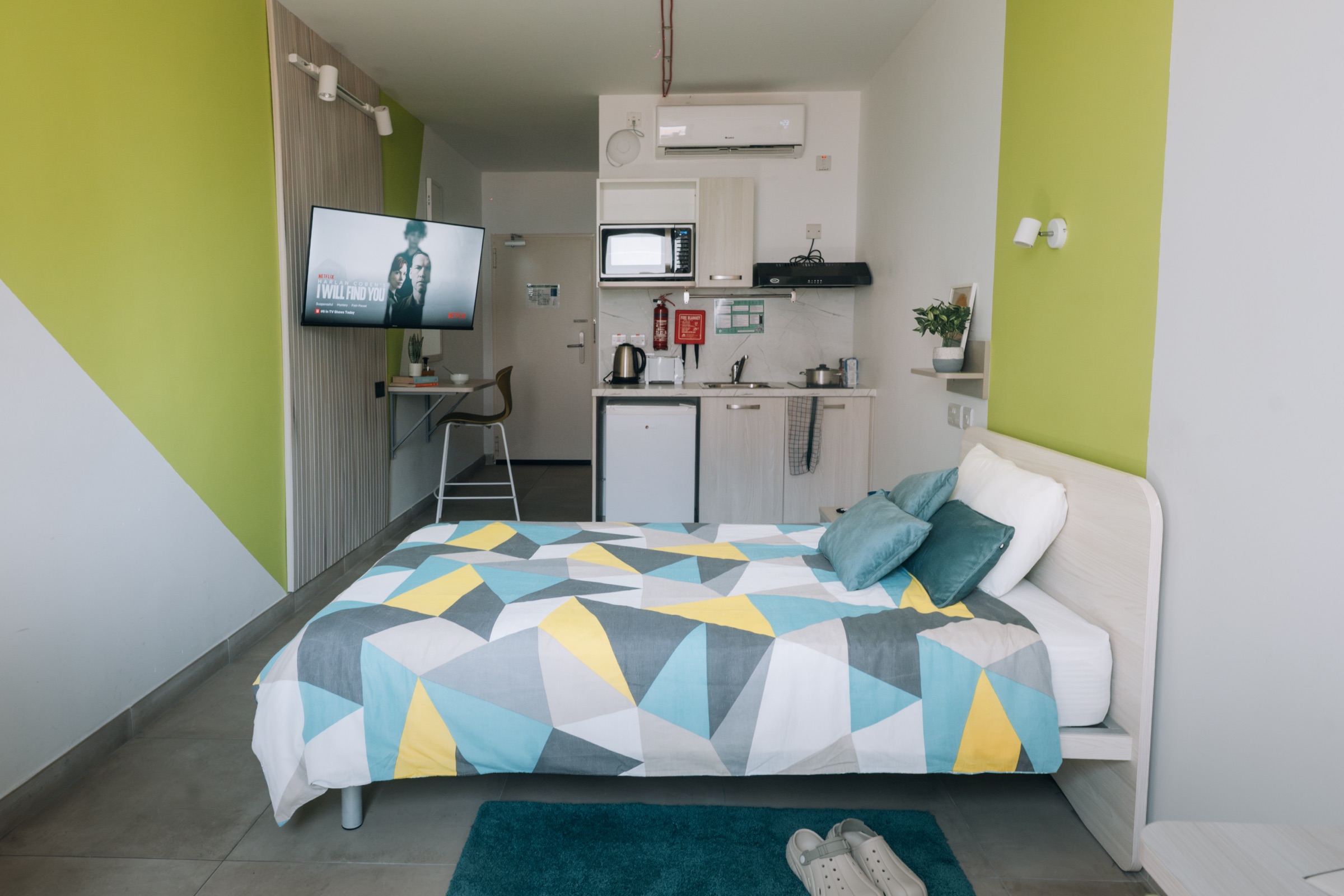 Solo room with a double bed facing the wall-mounted television and the in-room kitchen