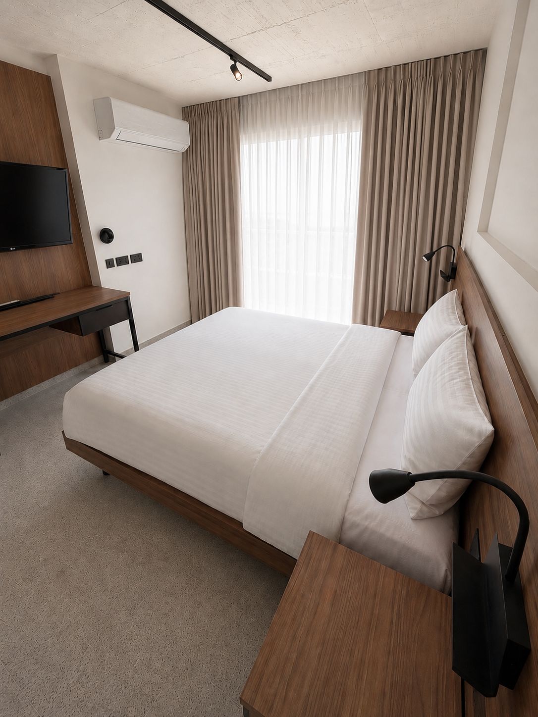 Select room with a double bed in white linen, a walnut desk and wall-mounted television, and a curtained full-height window