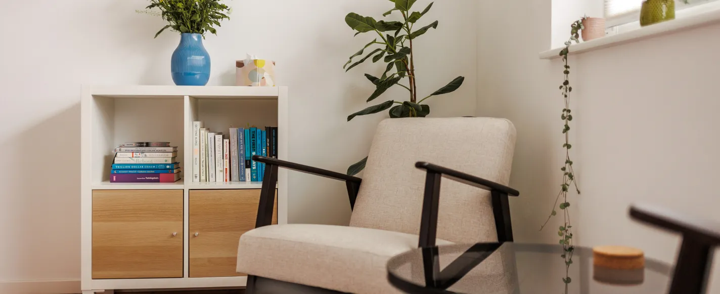 Heller Coaching-Raum mit Sessel, Bücherregal und Pflanze