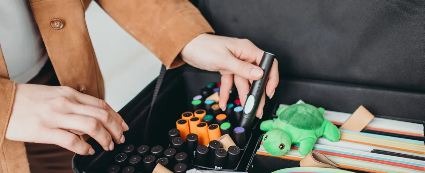 Hand greift nach bunten Stiften in einer Materialbox mit Coaching-Utensilien