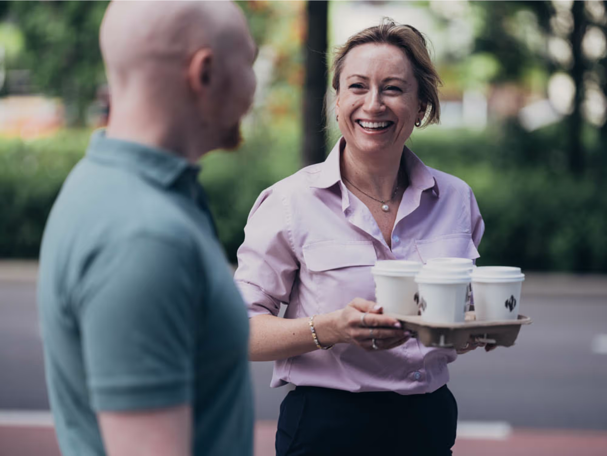 Colleague serving coffee to another outside.