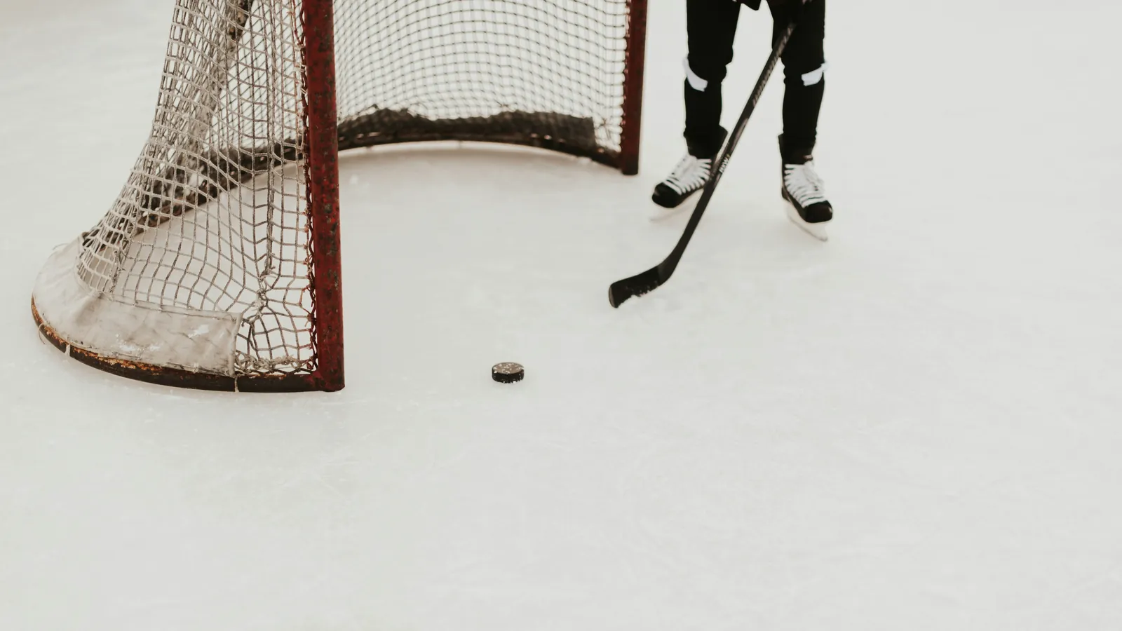 Athlète de hockey sur glace, crosse et palet devant la cage