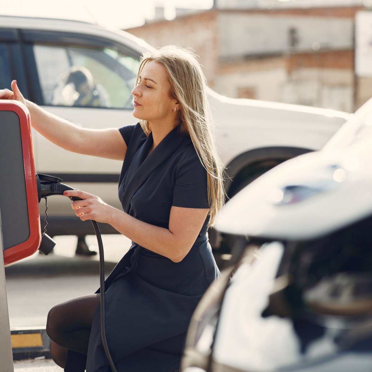 Personne branchant un câble de recharge sur un véhicule électrique