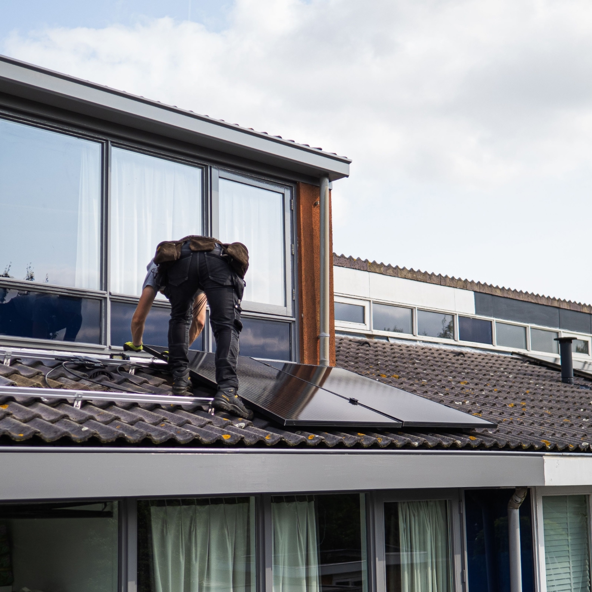 Technicien intervenant sur une installation photovoltaïque en toiture d'un bâtiment tertiaire