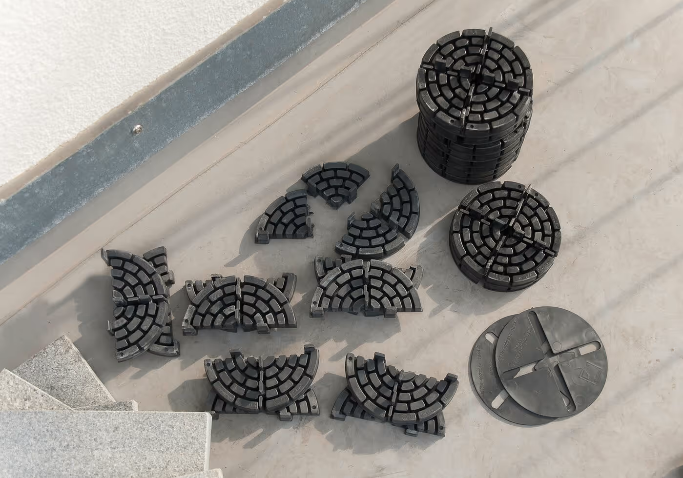 Schwarze, segmentierte PLATTENFIX Fugenkreuze und Rasenfugenkreuze auf einer Terrasse neben einer Natursteintreppe ausgelegt