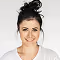 Smiling woman with dark hair tied up wearing a white top against a plain white background.