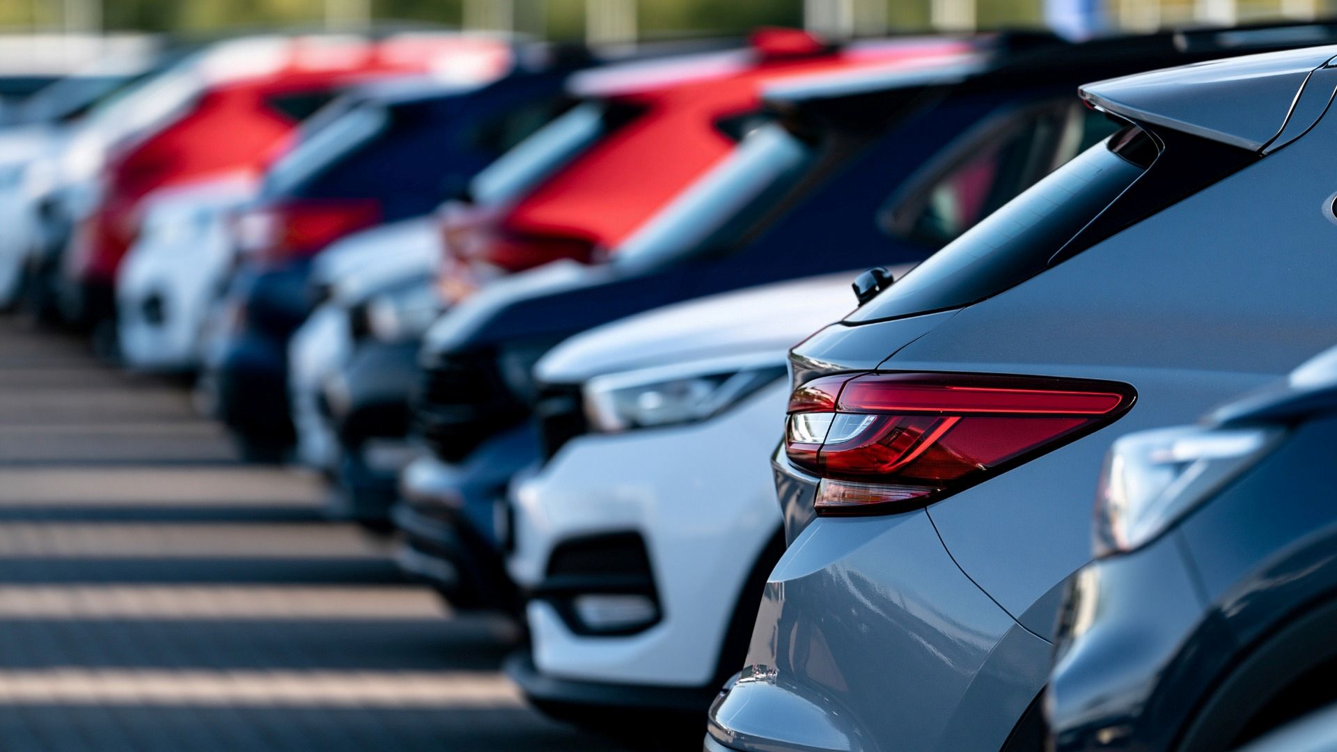 A row of cars parked nose to tail in a car park
