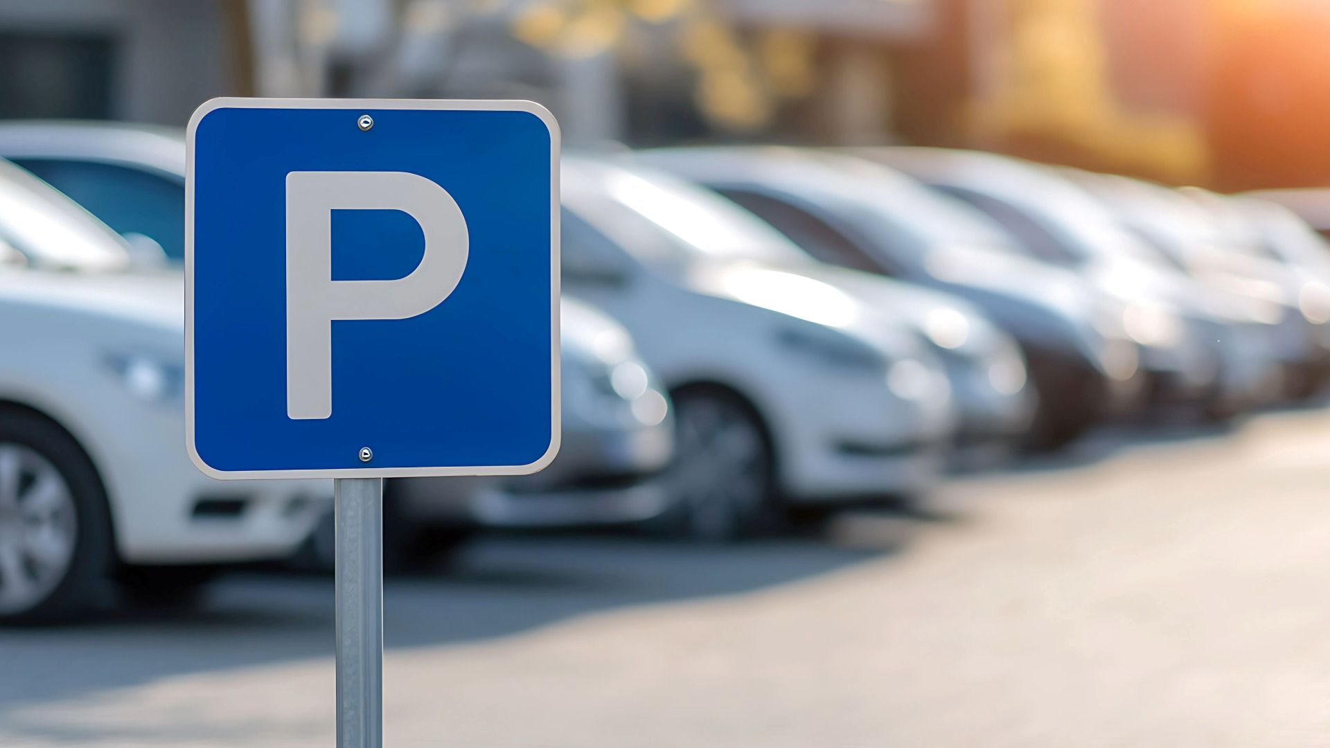 Parking sign in a car park with cars parked in rows behind it