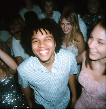 Smiling young man with dreadlocks and others having fun at a lively party.