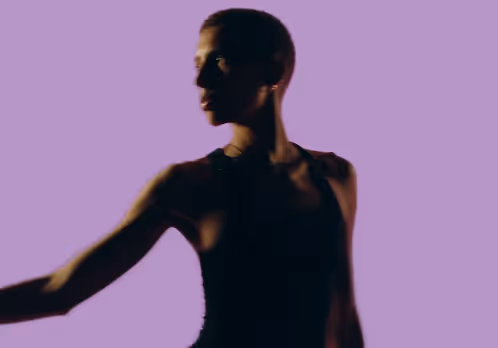 Silhouette of a person in a sleeveless top against a purple background, looking to the left.
