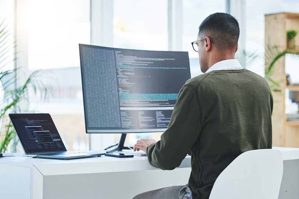 Sequel-Data-Systems-engineer-working-at-a-dual-monitor-workstation-in-a-modern-office