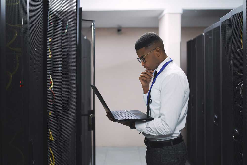 Sequel-Data-Systems-engineer-reviewing-infrastructure-between-server-racks