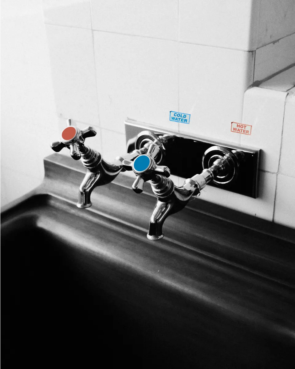 A pair of water taps labeled hot and cold, but the handles are swapped - hot dispenses cold water and cold dispenses hot.