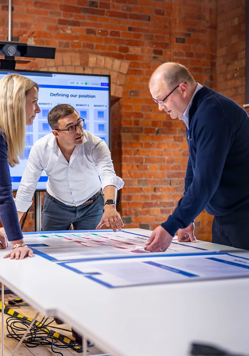 New Era Marketing colleagues defining brand positioning around a printed workshop board