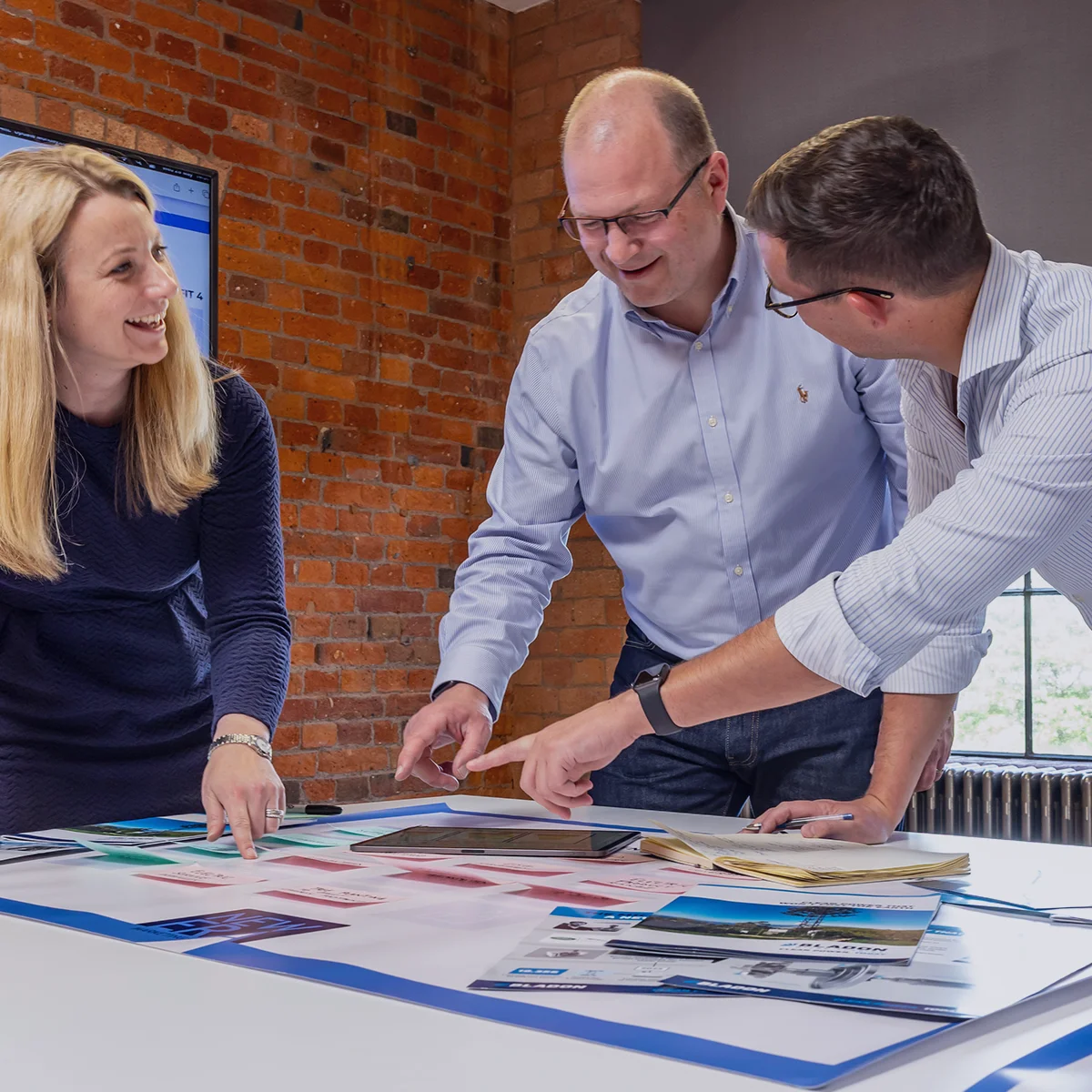 Three colleagues reviewing marketing materials around a table