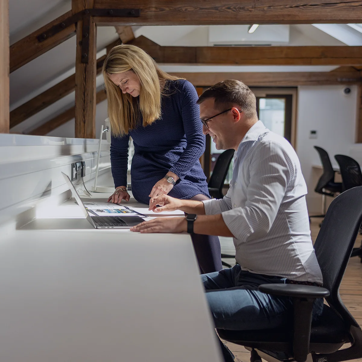 Two colleagues reviewing work together at a standing desk