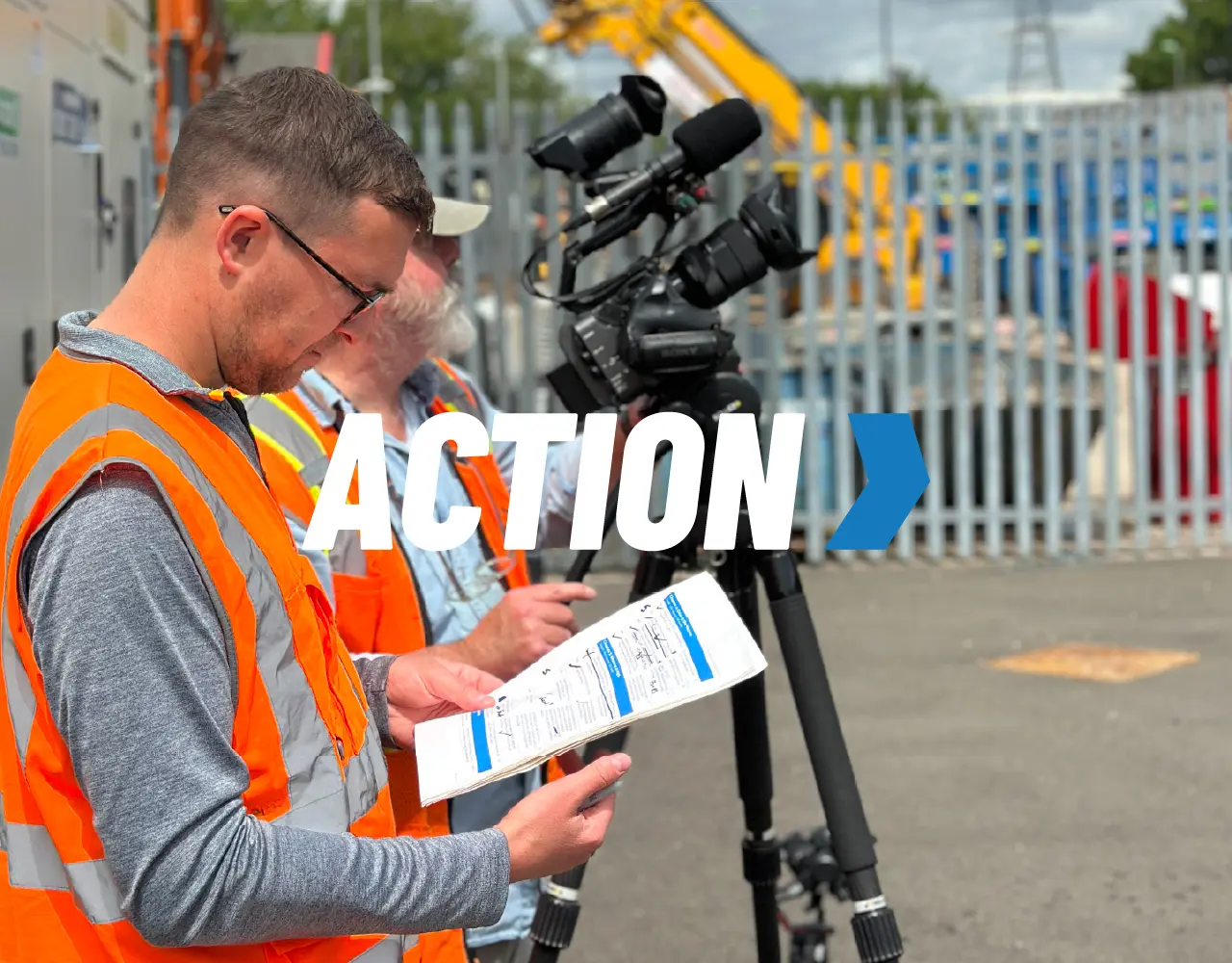 A man in an orange vest is holding a piece of paper that says action.