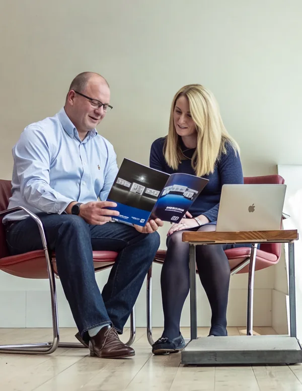Two New Era colleagues reviewing a brochure together