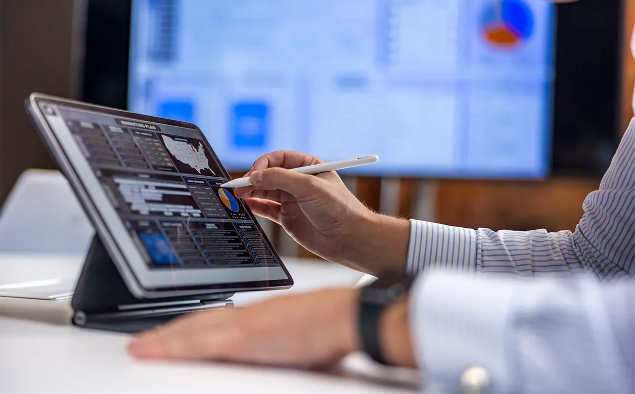 Marketing professional reviewing a marketing plan and data dashboards on a tablet