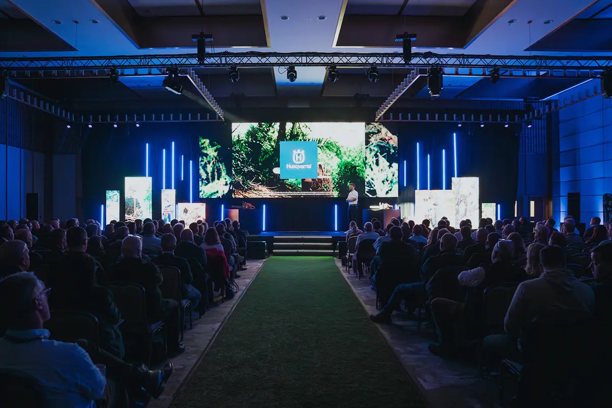 Conference audience facing a stage with large screens and lighting