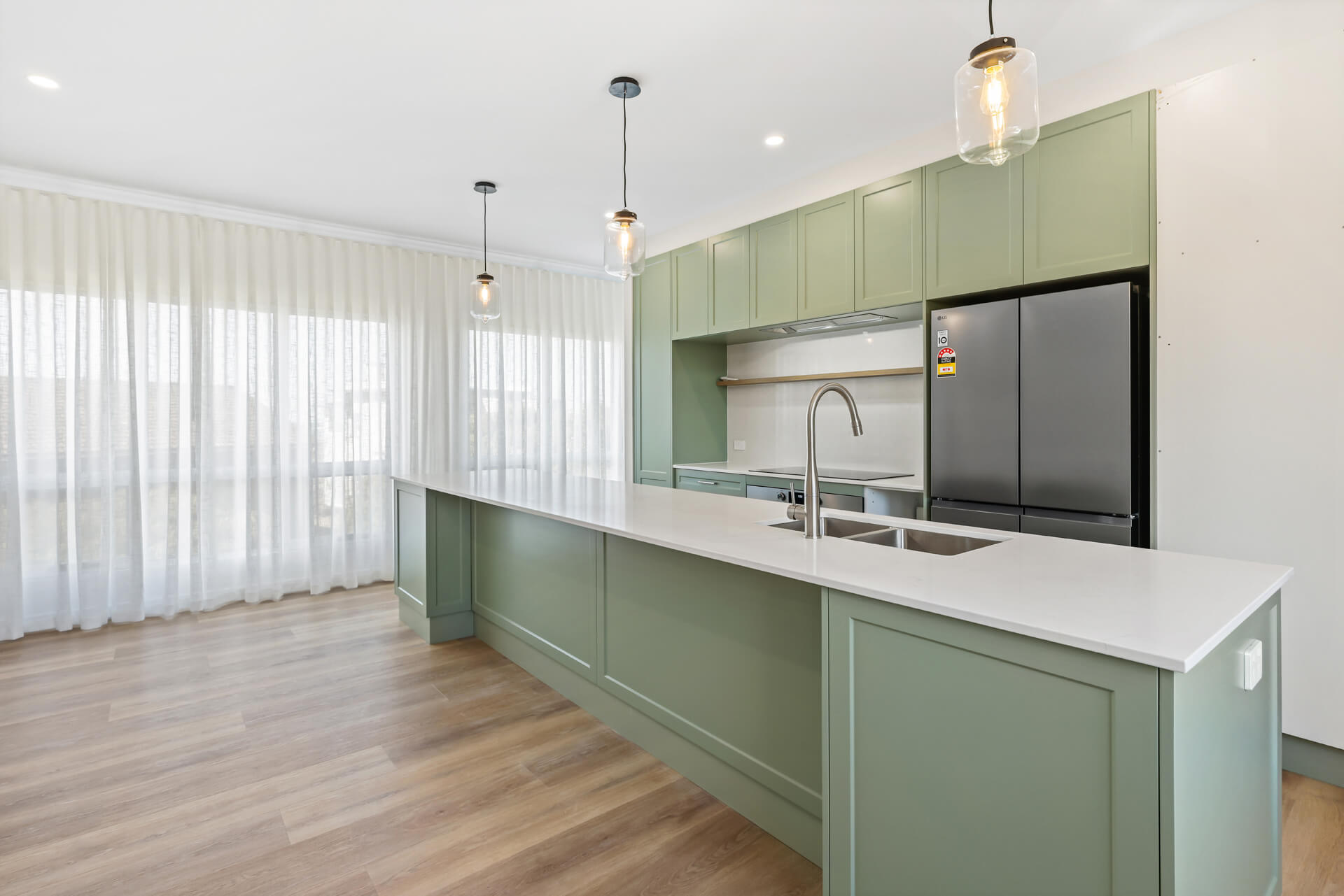 Sage green kitchen with long stone island bench and pull-out mixer at Victoria St, Victor Harbor