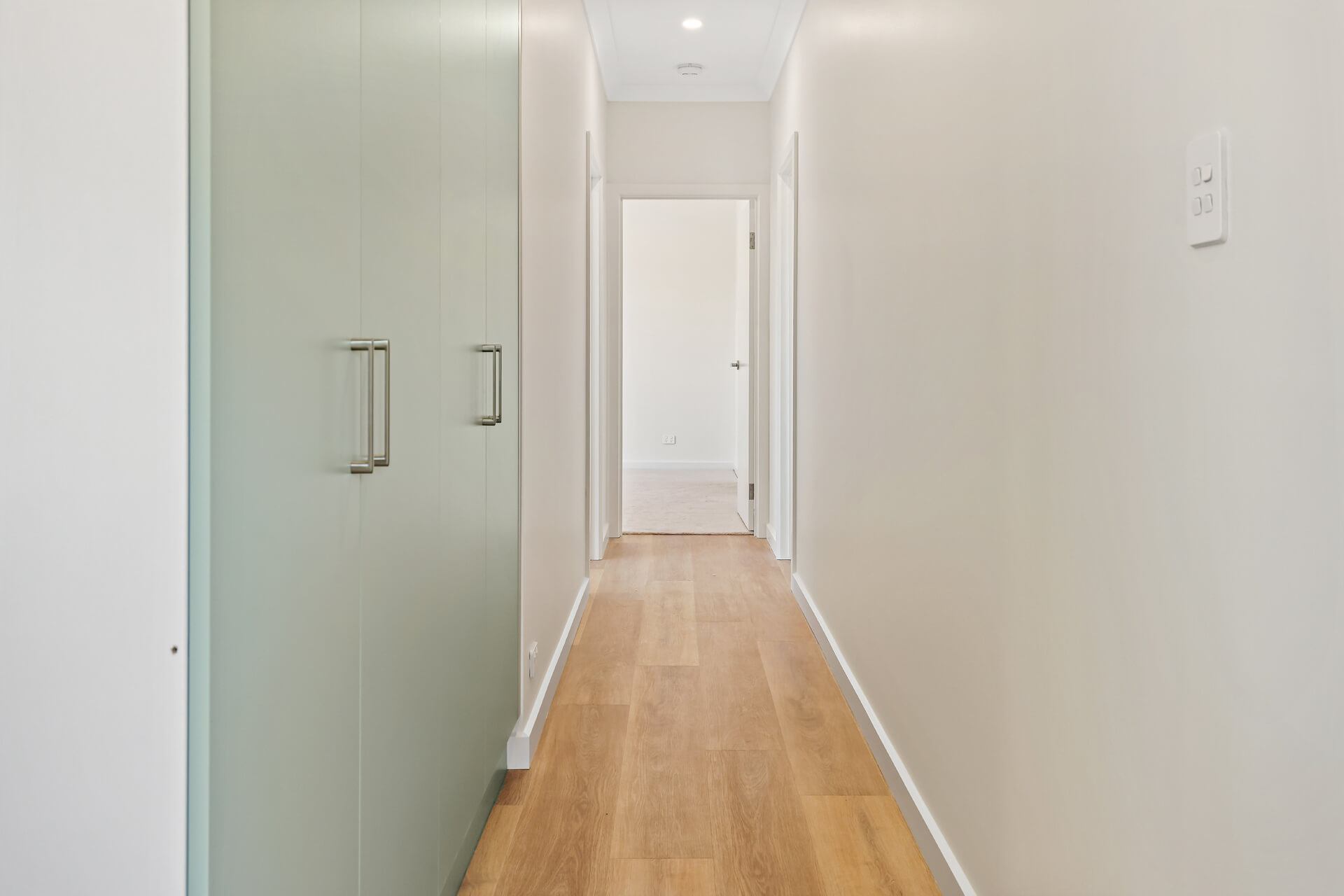 Hallway with full-height sage green storage cupboards and timber flooring at Victoria St, Victor Harbor
