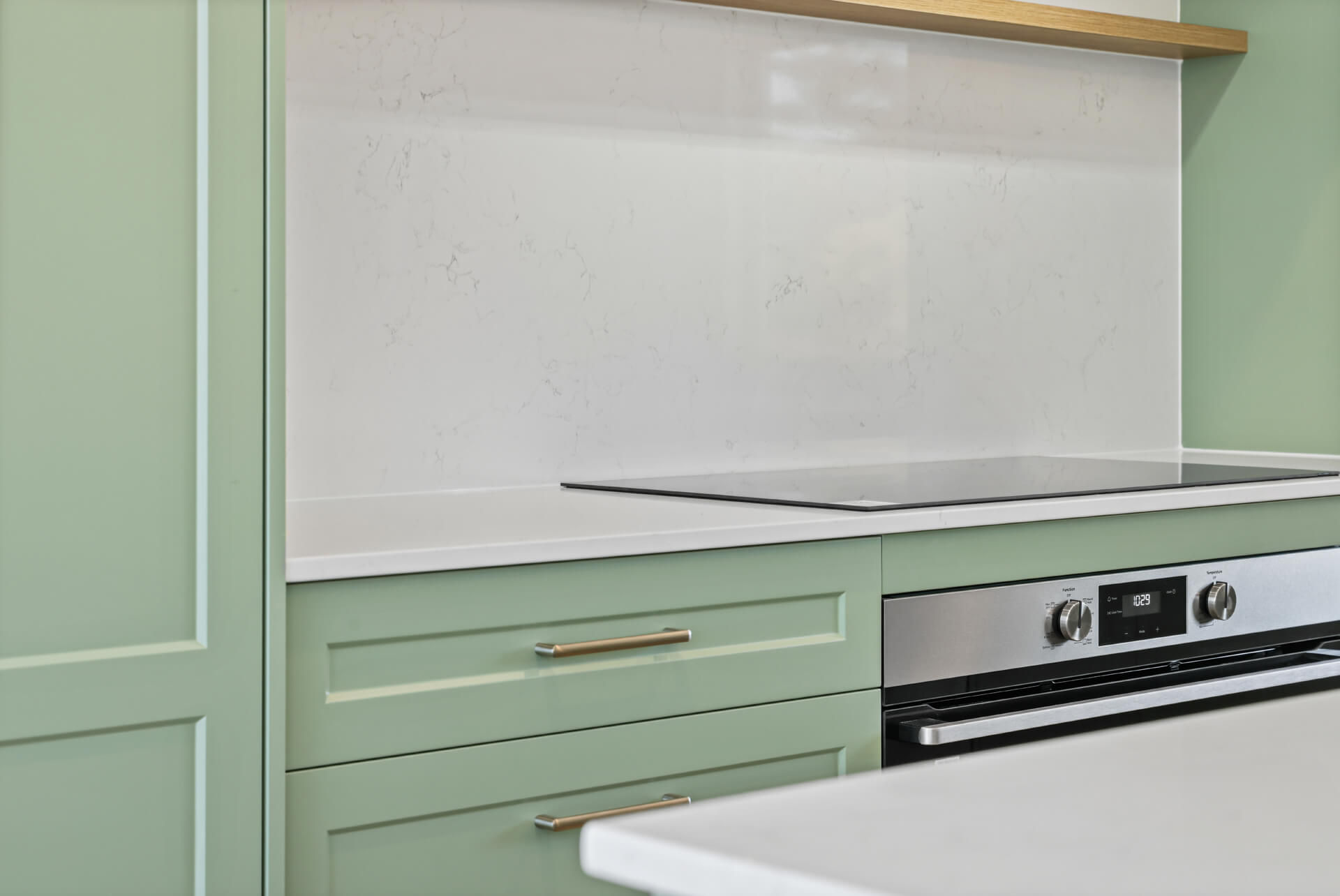 Induction cooktop and brass handles on sage green cabinetry at Victoria St, Victor Harbor