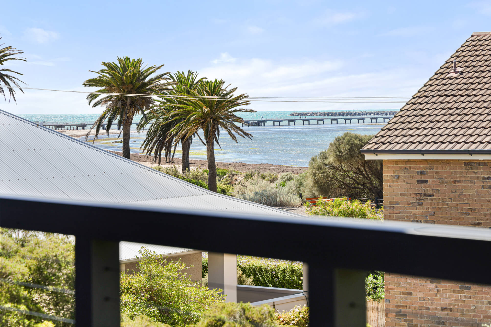 Balcony view through Norfolk pines to the Granite Island causeway from Victoria St, Victor Harbor