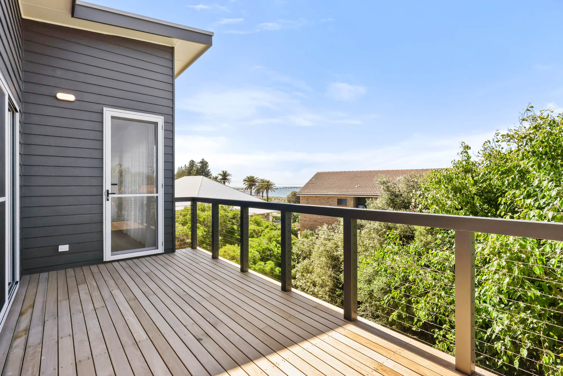 Upper balcony with timber decking, dark cladding and sliding doors at Victoria St, Victor Harbor