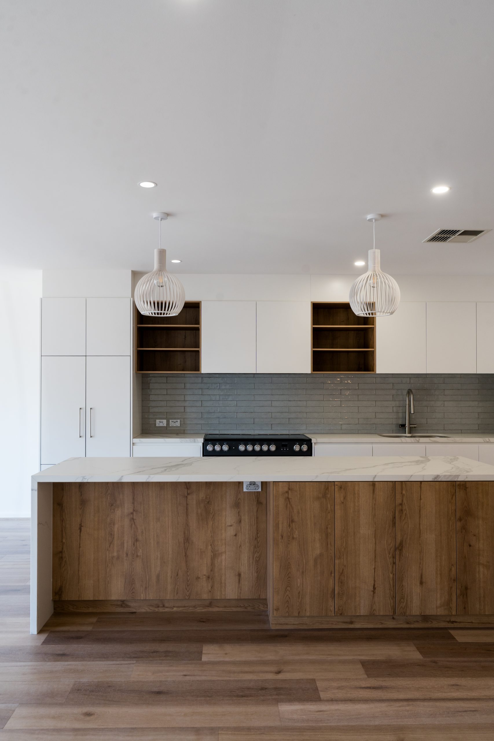 Kitchen with oak island, white cabinetry and grey handmade tile splashback at Henry St, Port Elliot