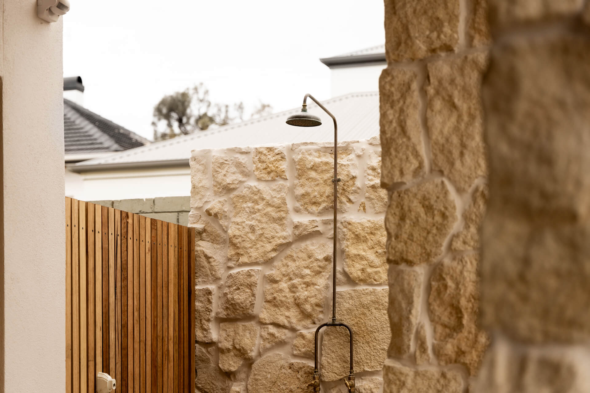 Outdoor shower mounted on a limestone wall beside timber screening at Henry St, Port Elliot