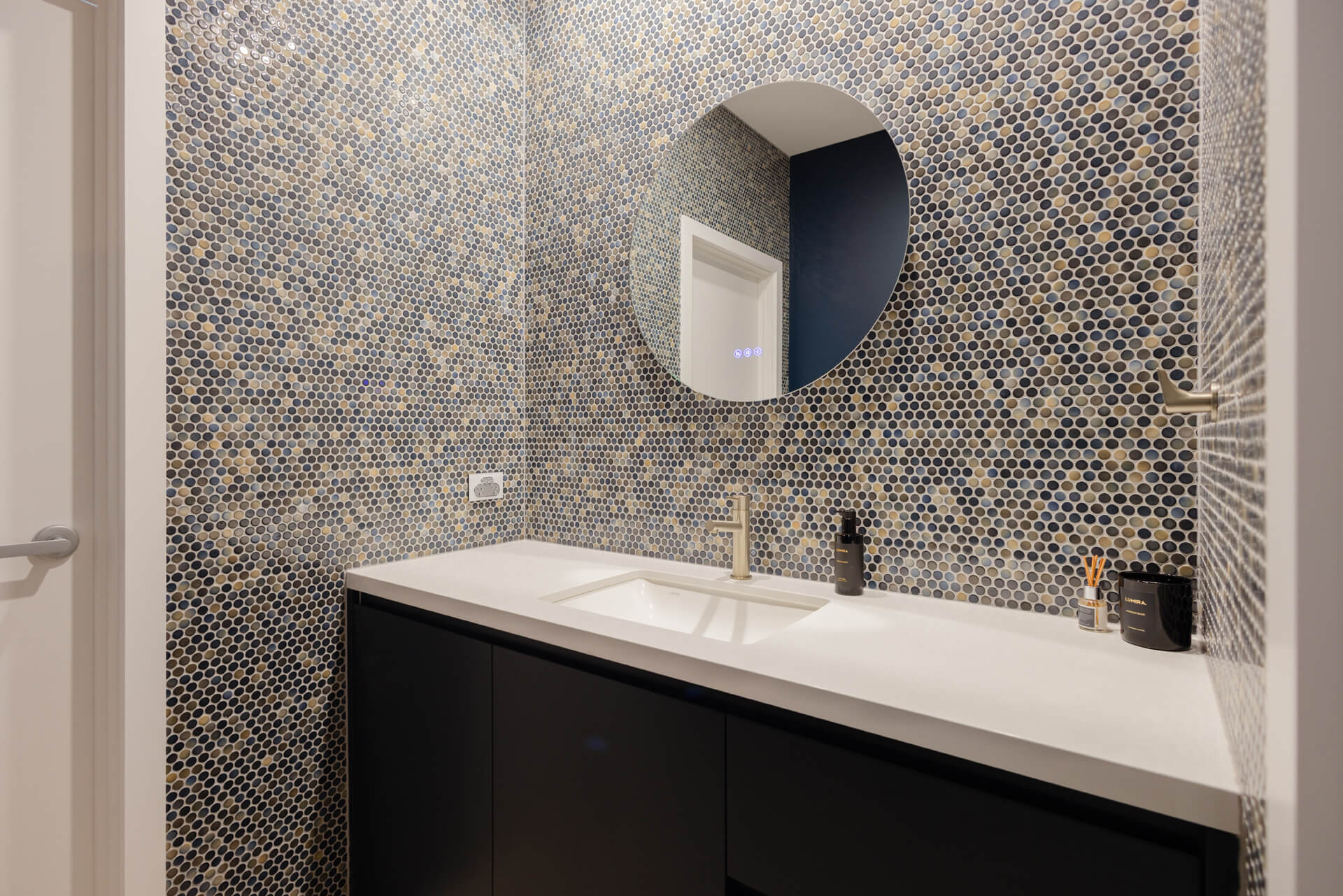 Powder room with penny round mosaic feature wall and round mirror at Henry St, Port Elliot