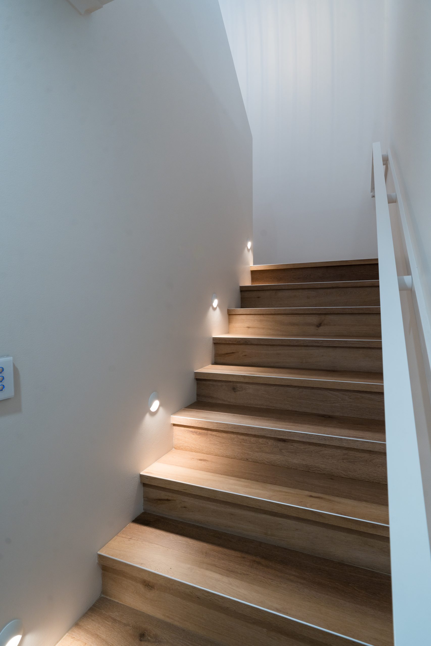Timber staircase with recessed wall lights and white balustrade at Henry St, Port Elliot