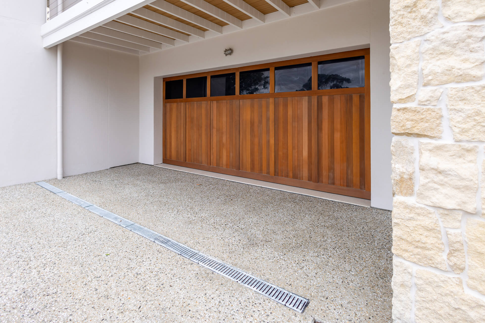 Cedar-look garage door with exposed aggregate driveway and strip drain at Henry St, Port Elliot