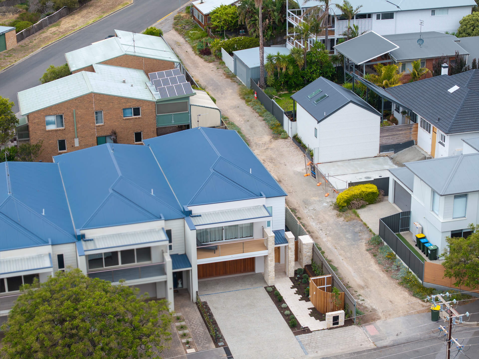 Aerial view of the completed Henry St duplex with blue roof and landscaped frontage, Port Elliot