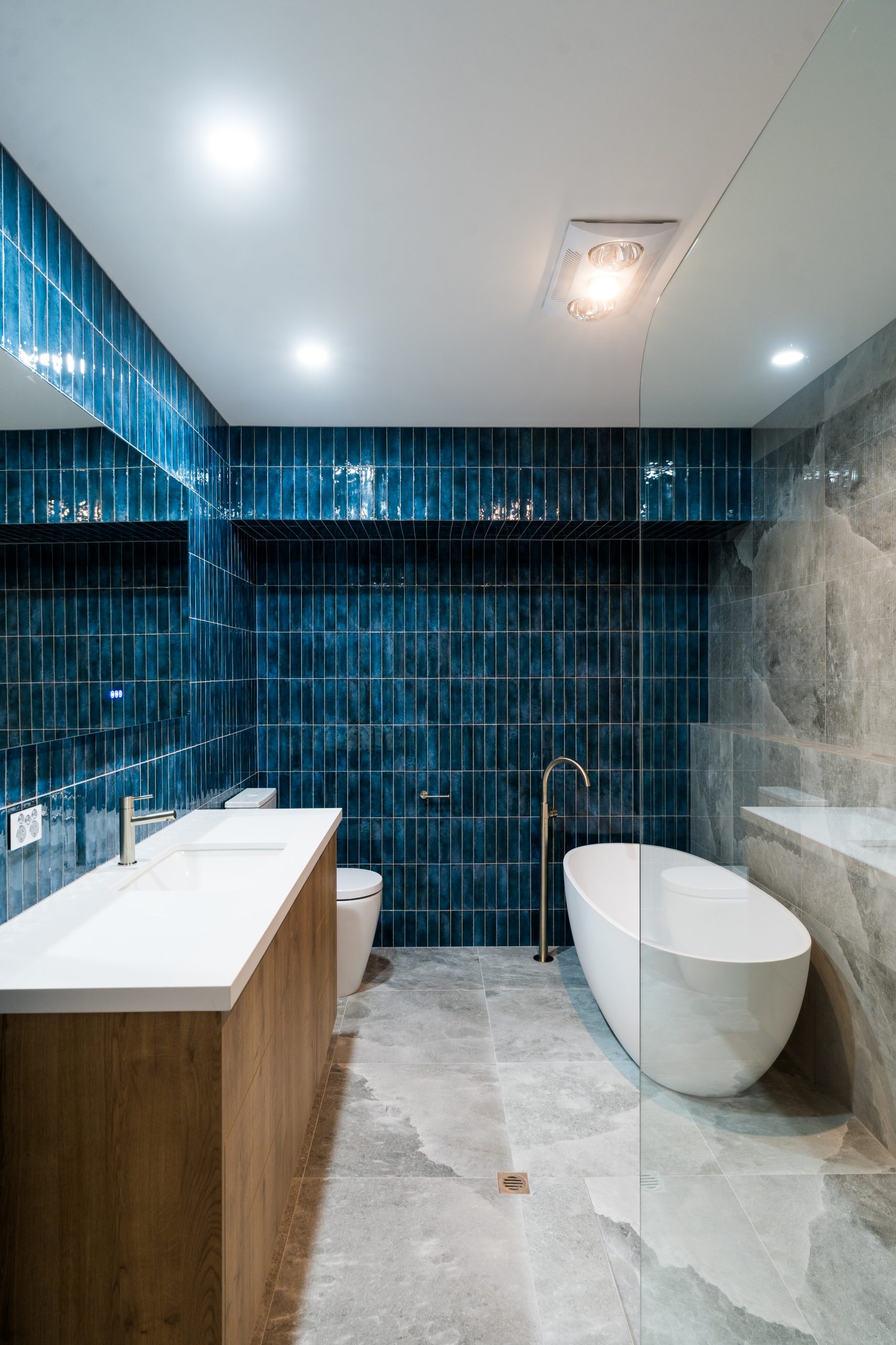 Bathroom with deep blue feature tiles, freestanding bath and brass floor-mounted bath filler at Henry St, Port Elliot