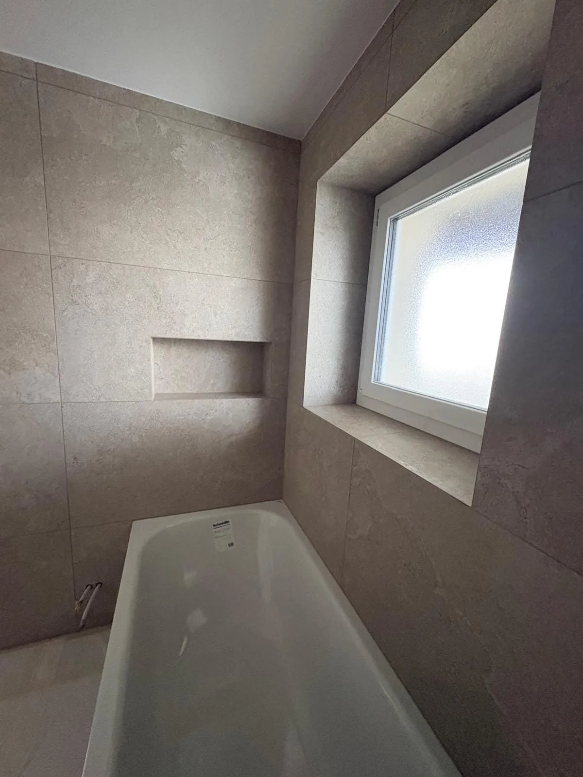 Baignoire encastrée sous la fenêtre avec niche dans une salle de bain à Bogis-Bossey