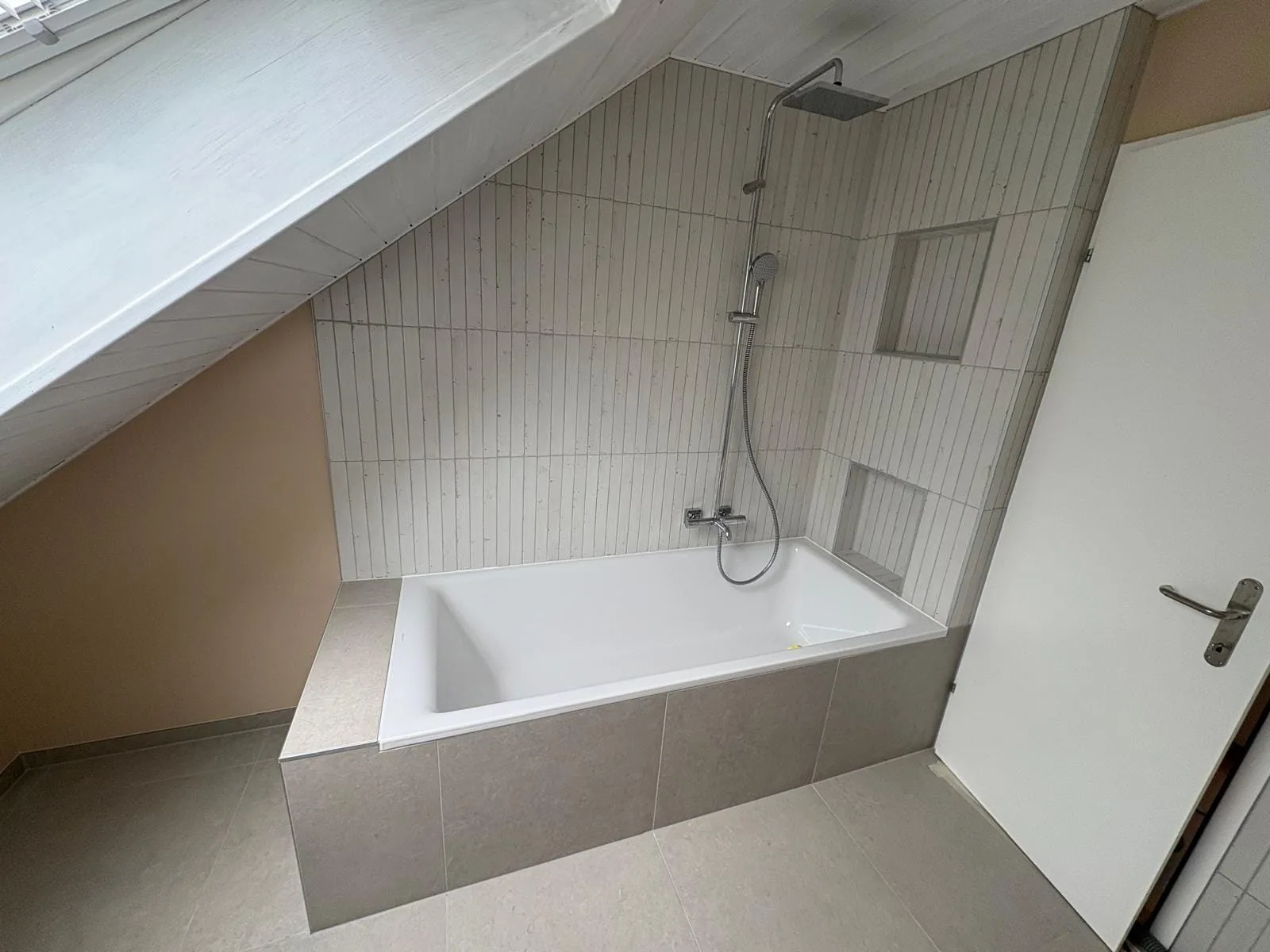 Baignoire carrelée dans une salle de bain rénovée sous combles à Trélex