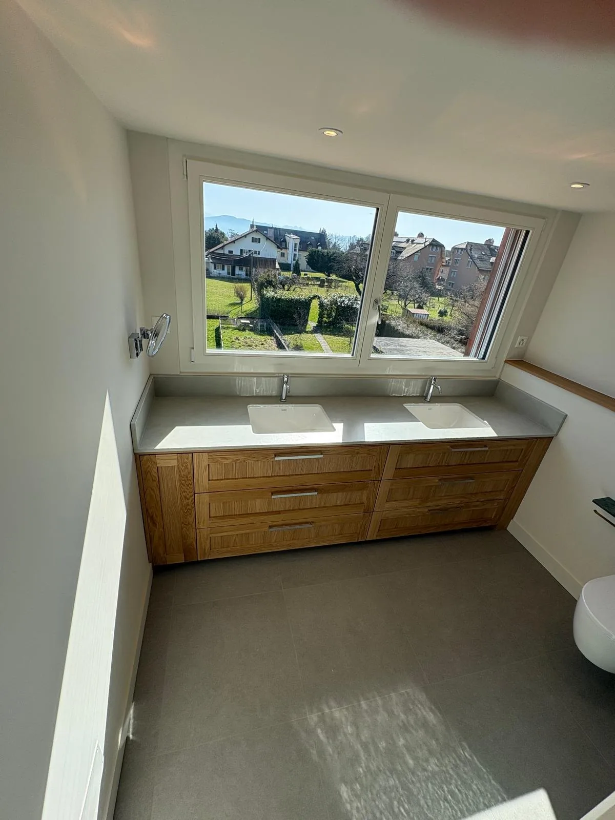 Meuble double vasque et grande fenêtre dans une salle de bain à Chéserex