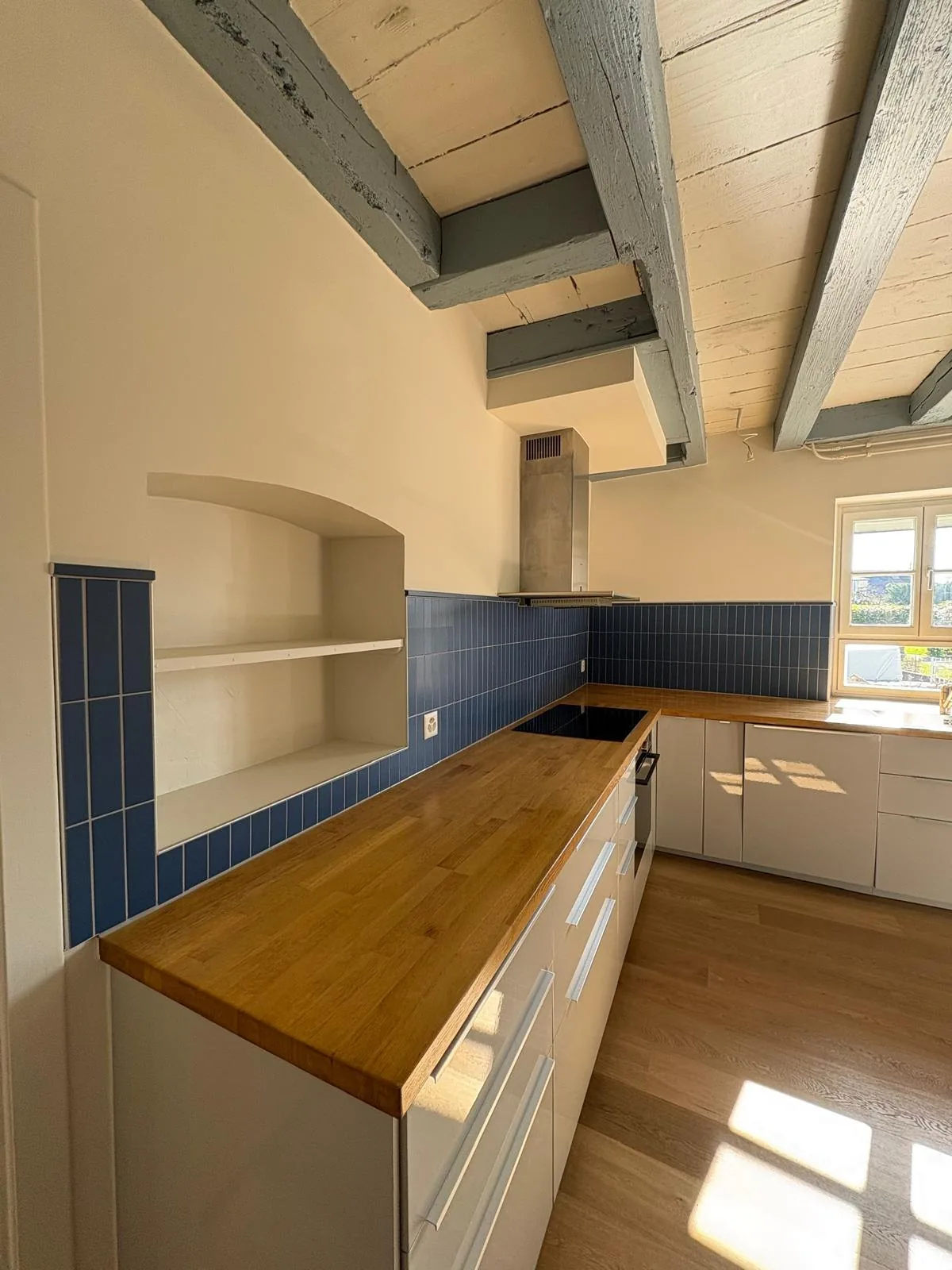 Crédence de cuisine carrelée le long d'un plan de travail, avec niche murale et plaque de cuisson