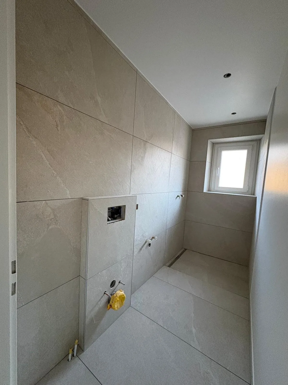Espace WC carrelé avec fenêtre dans une salle de bain à Bogis-Bossey