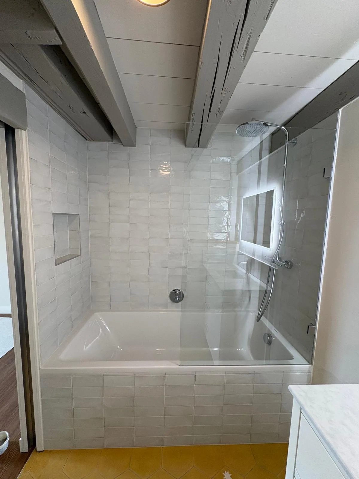 Baignoire avec paroi vitrée et douche de pluie dans une salle de bain à Chéserex