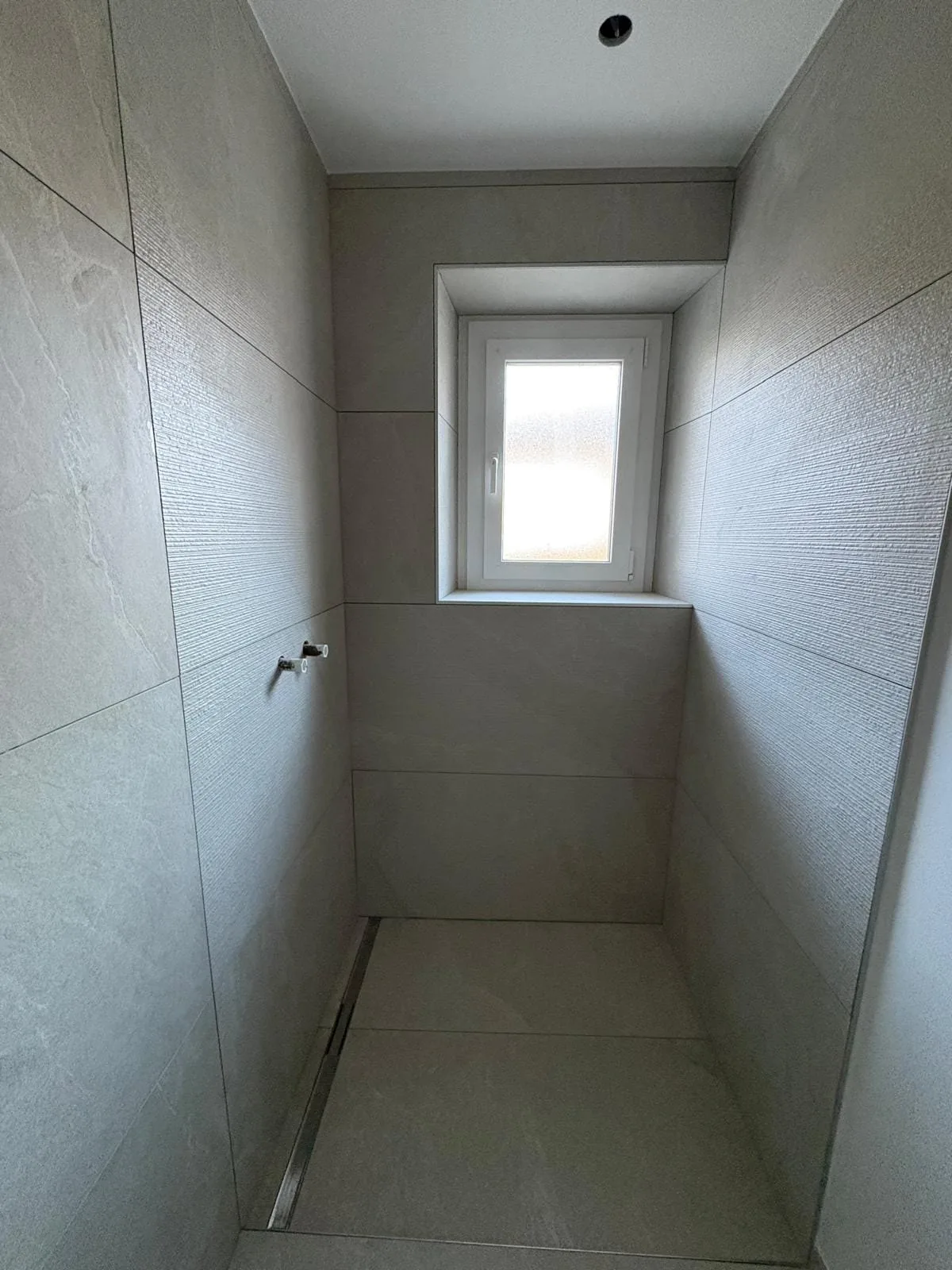 Douche avec caniveau d'écoulement au sol dans une salle de bain à Bogis-Bossey