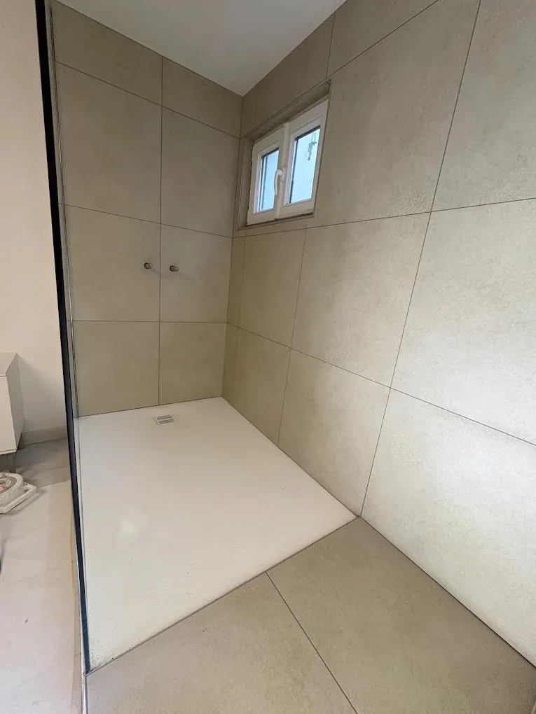 Receveur de douche extra-plat et parois carrelées beige dans une douche à l'italienne à Trélex