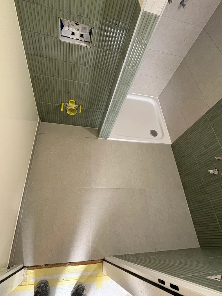 Sol carrelé et receveur dans une salle de douche à Trélex